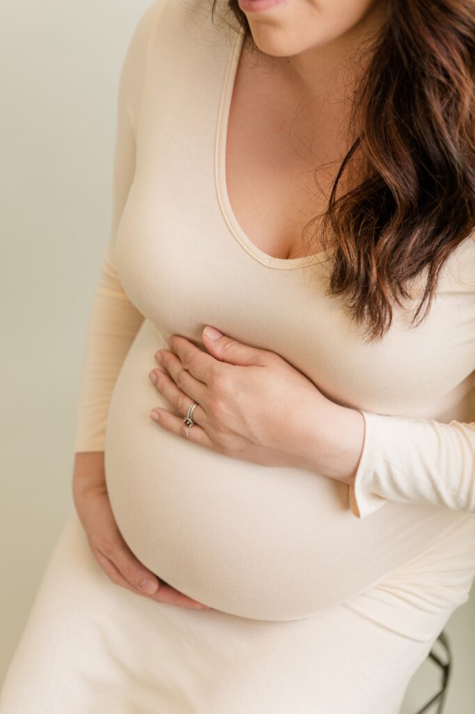 Woman holding belly in studio maternity photo