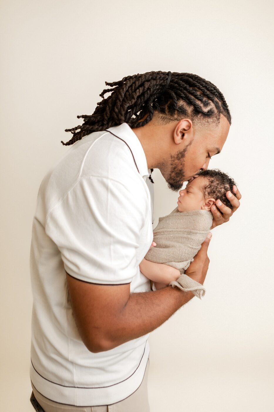 studio photo of dad kissing baby boy by a bay area newborn photographer