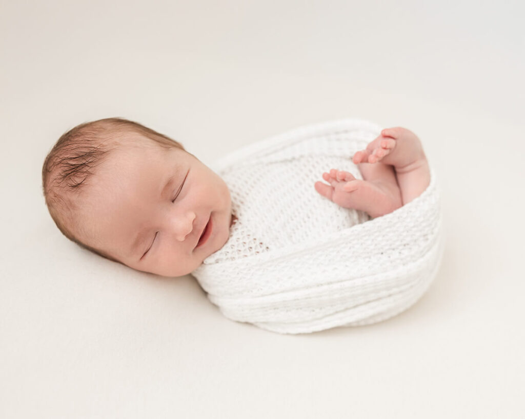 baby boy smiling in his sleep during his newborn photography session