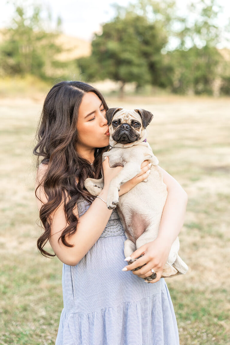 Pregnant mom holding her dog and kissing it